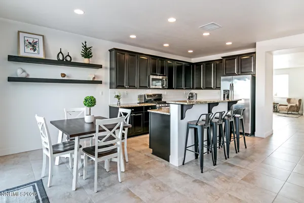 a kitchen with stainless steel appliances kitchen island granite countertop a table and chairs in it