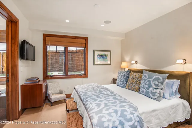 a living room with furniture a flat screen tv and a floor to ceiling window