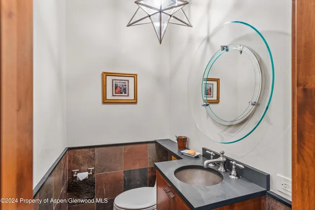 a view of a dining room and livingroom with furniture wooden floor a rug a painting and a chandelier