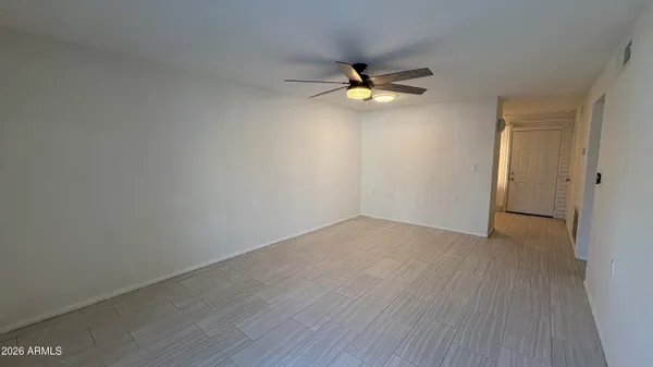 a view of an empty room with wooden floor and window