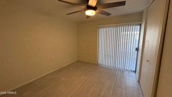 an empty room with wooden floor fan and windows