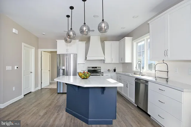 a kitchen with kitchen island granite countertop a sink a counter space appliances and cabinets