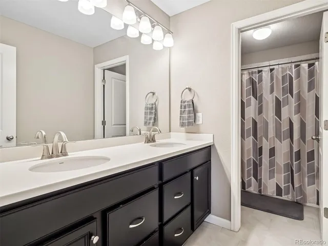 a bathroom with double vanity sinks a vanity a lamp and a mirror