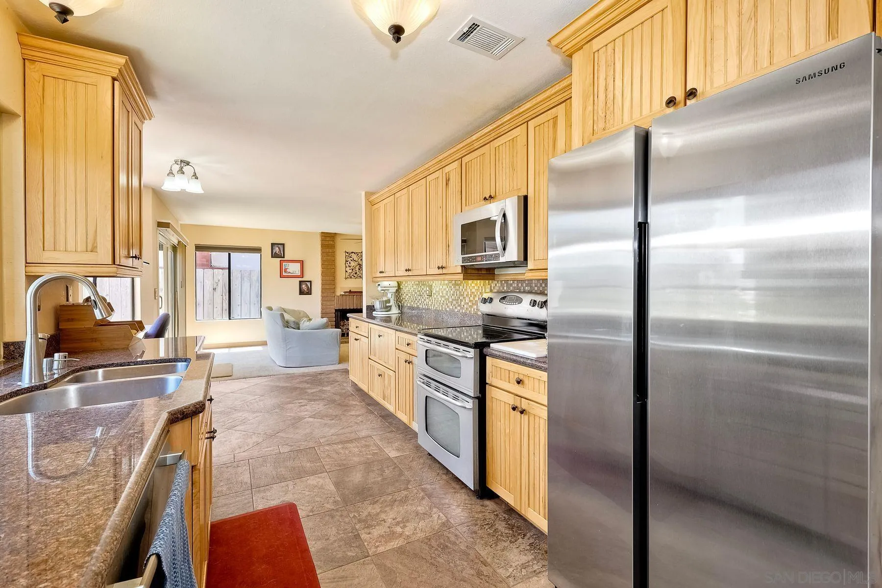 3805 Catamarca Drive San Diego, CA 92124 - Photo 58 of 59 a kitchen with stainless steel appliances granite countertop a refrigerator a stove and a sink with couches