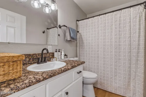 a bathroom with a granite countertop sink a toilet and a mirror