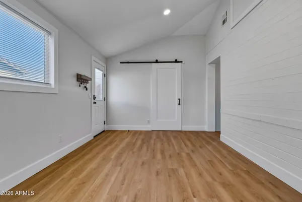 a view of an empty room with wooden floor and a window