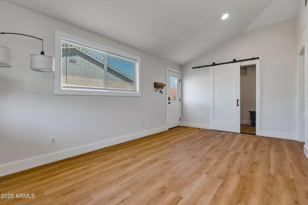a view of an empty room with wooden floor and a window