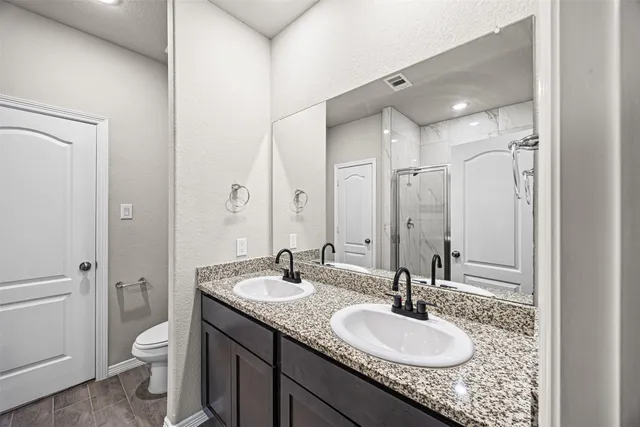 a bathroom with a granite countertop sink toilet and a mirror