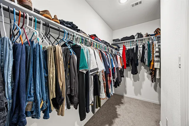 a walk in closet with clothes