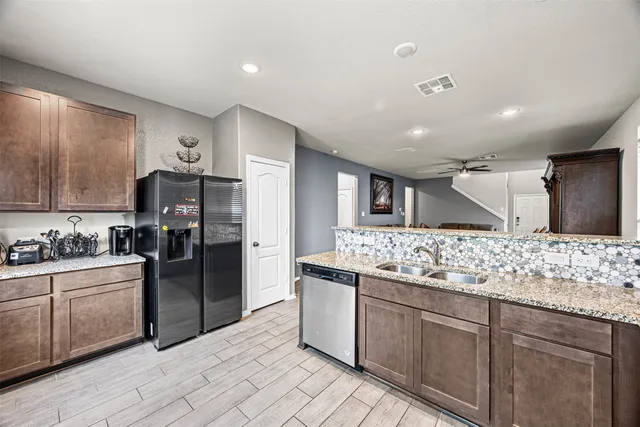 a kitchen with stainless steel appliances kitchen island granite countertop a refrigerator and a sink