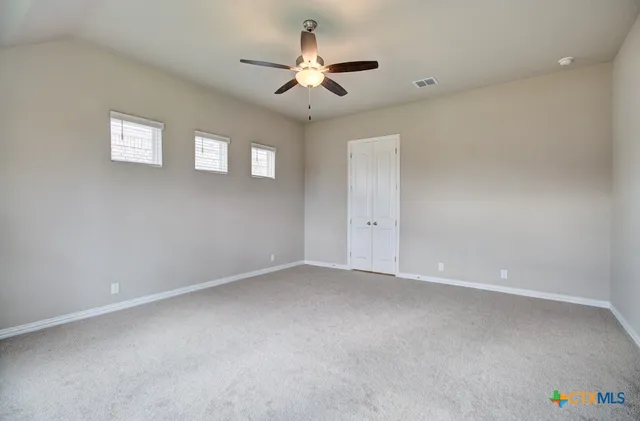 an empty room with a ceiling fan and a window