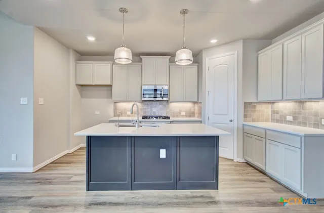 a view of a kitchen counter space a sink wooden floor and stainless steel appliances