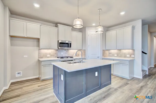 a kitchen with a sink a stove a refrigerator and white cabinets