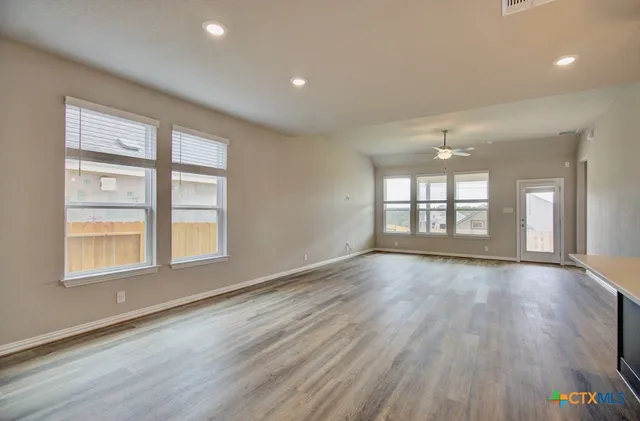 a view of an empty room with a window and wooden floor