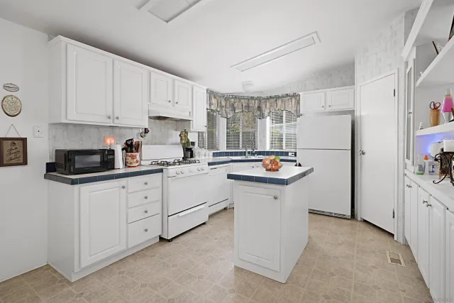 a kitchen with white cabinets and refrigerator