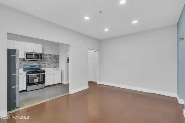a view of kitchen with stainless steel appliances cabinets and empty room