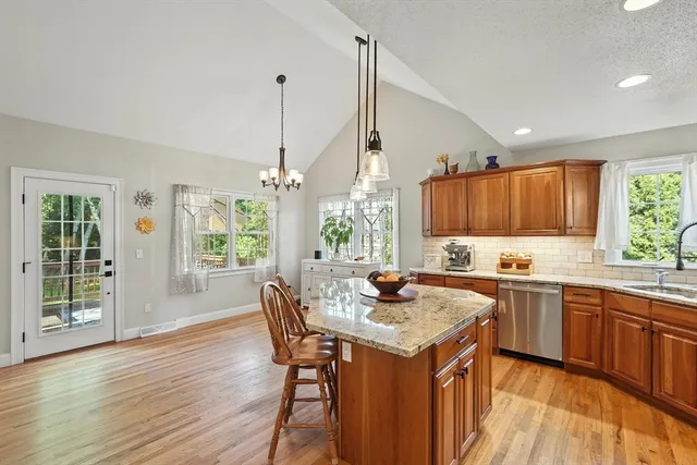 a kitchen with stainless steel appliances a sink a stove a refrigerator cabinets and wooden floor