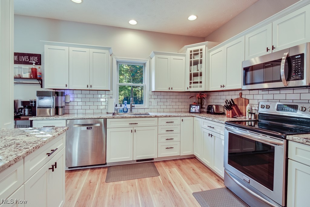 132 Timber Ridge Drive, Unit RDR Elyria, OH 44035 - Photo 17 of 41 Kitchen featuring appliances with stainless steel finishes, white cabinetry, light wood-type flooring, and backsplash
