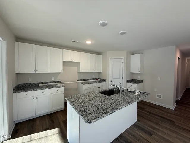 a kitchen with granite countertop a sink a stove and cabinets