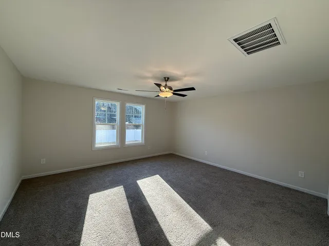 an empty room with windows and chandelier fan