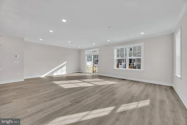 a view of empty room with wooden floor and window