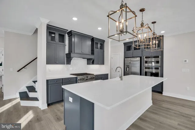 a large kitchen with kitchen island a stove a sink a refrigerator and a wooden floor