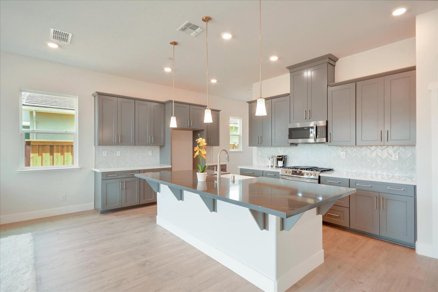 8157 Poppy Ridge Road Elk Grove, CA 95757 - Photo 11 of 42 a large kitchen with kitchen island a large counter top space a sink stainless steel appliances and cabinets