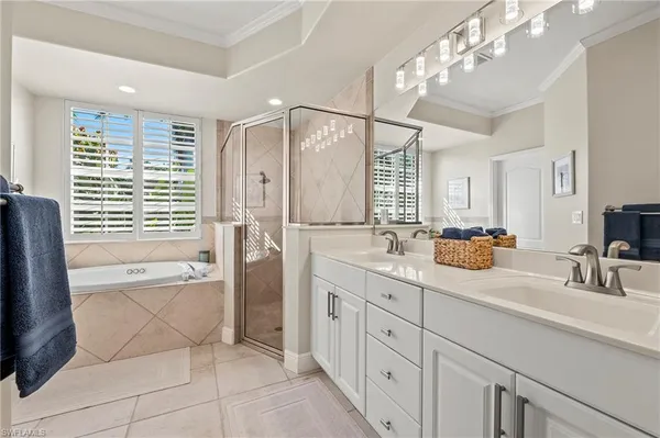 a bathroom with a tub a sink double vanity and a mirror
