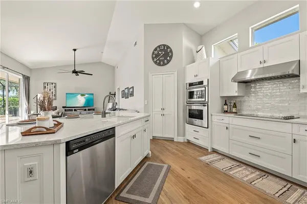 a kitchen with cabinets stainless steel appliances and a clock