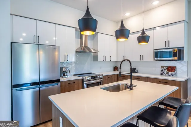a kitchen with stainless steel appliances a refrigerator a sink a stove and white cabinets