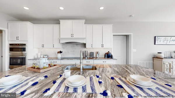 a open kitchen with stainless steel appliances granite countertop a sink a stove a dining table and chairs with wooden floor