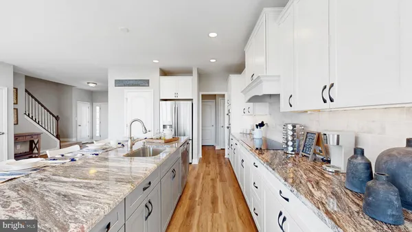 a large room with kitchen island a large counter top space a sink stainless steel appliances and cabinets