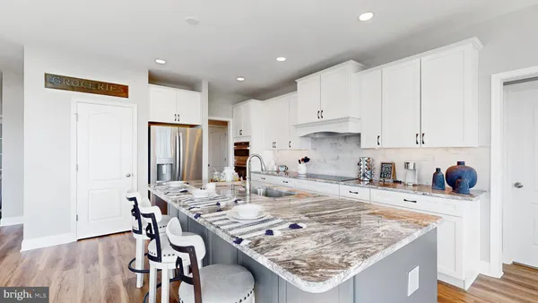a kitchen with granite countertop kitchen island stainless steel appliances a sink refrigerator and white cabinets