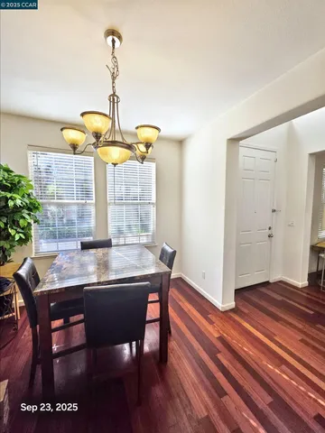 a dining room with wooden floor a chandelier a wooden table and chairs