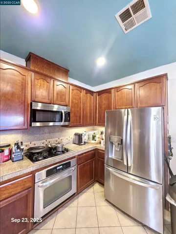 a kitchen with stainless steel appliances granite countertop a refrigerator a sink dishwasher a stove with wooden cabinets and floor