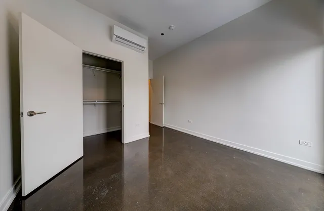 a view of empty room with wooden floor and refrigerator