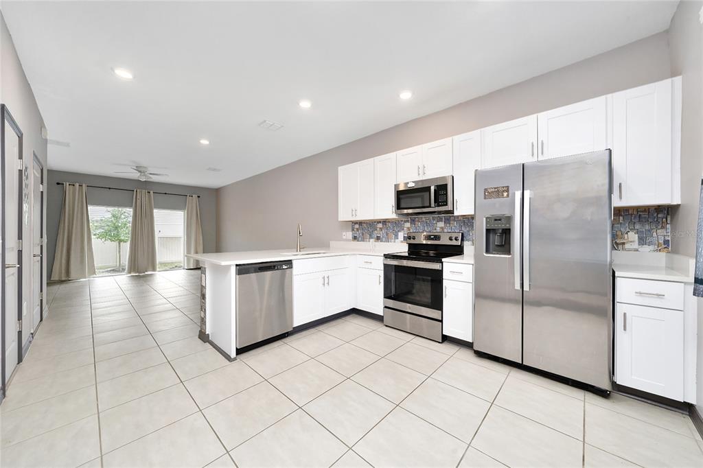 2060 Viewfinder Street Kissimmee, FL 34758 - Photo 8 of 23 a kitchen with granite countertop a refrigerator and a stove top oven