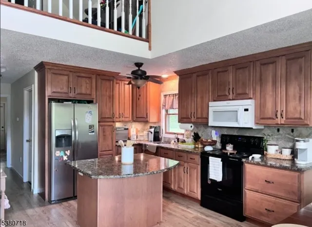 a kitchen with granite countertop a sink a counter top space cabinets and stainless steel appliances