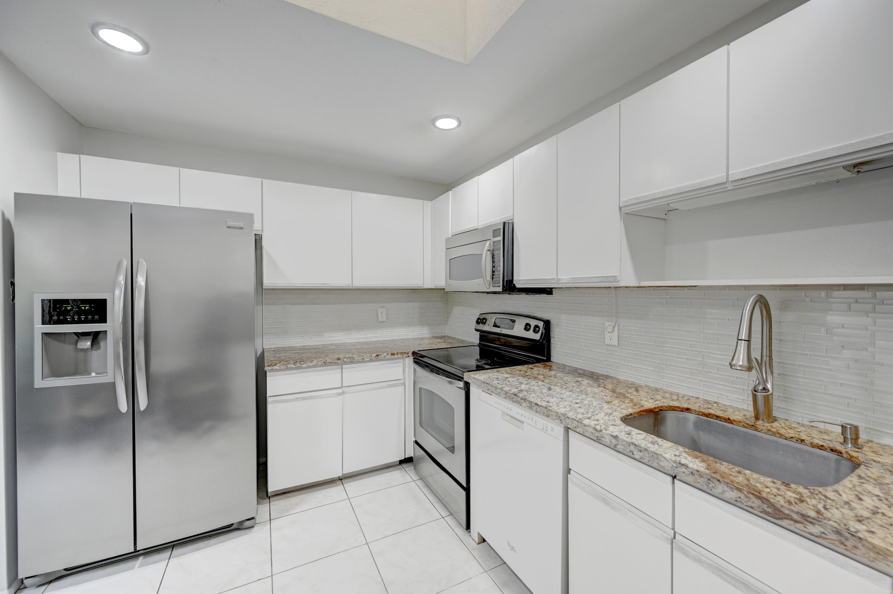 23328 Southwest 58th Avenue, Unit C Boca Raton, FL 33428 - Photo 12 of 35 a kitchen with granite countertop a sink stainless steel appliances and white cabinets