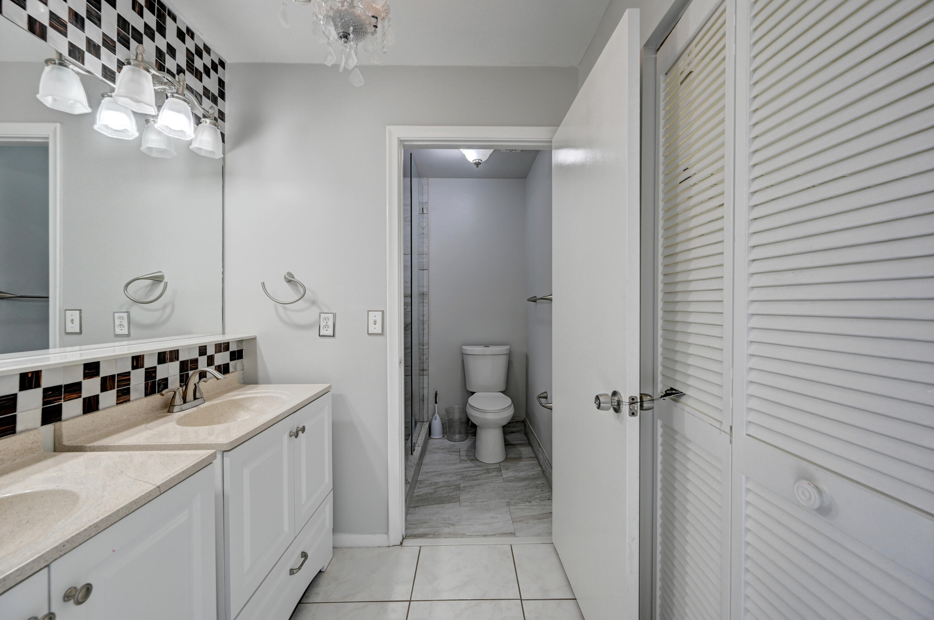 23328 Southwest 58th Avenue, Unit C Boca Raton, FL 33428 - Photo 24 of 35 a bathroom with a double vanity sink mirror and toilet