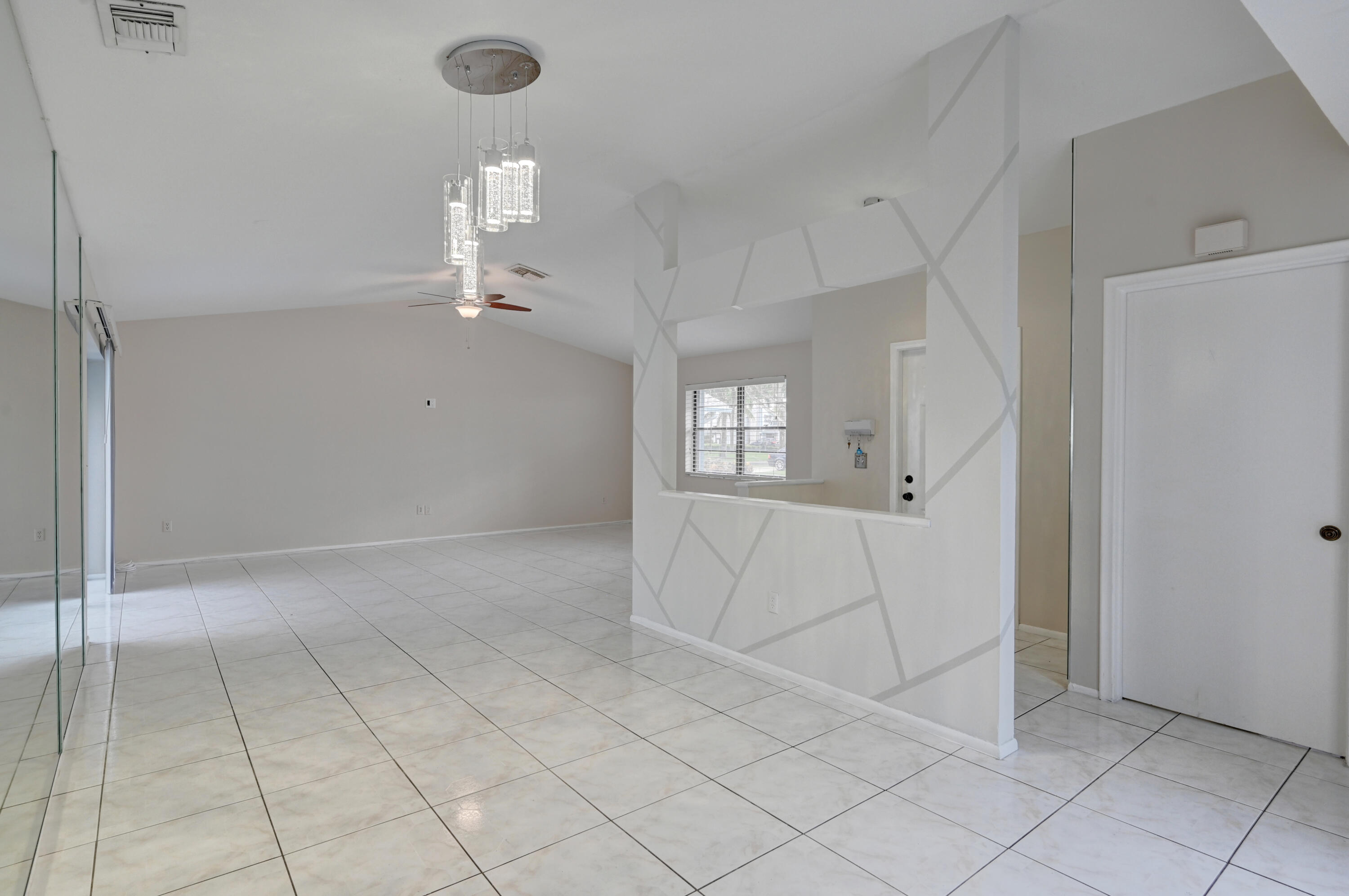 23328 Southwest 58th Avenue, Unit C Boca Raton, FL 33428 - Photo 9 of 35 an empty room with chandelier fan and windows
