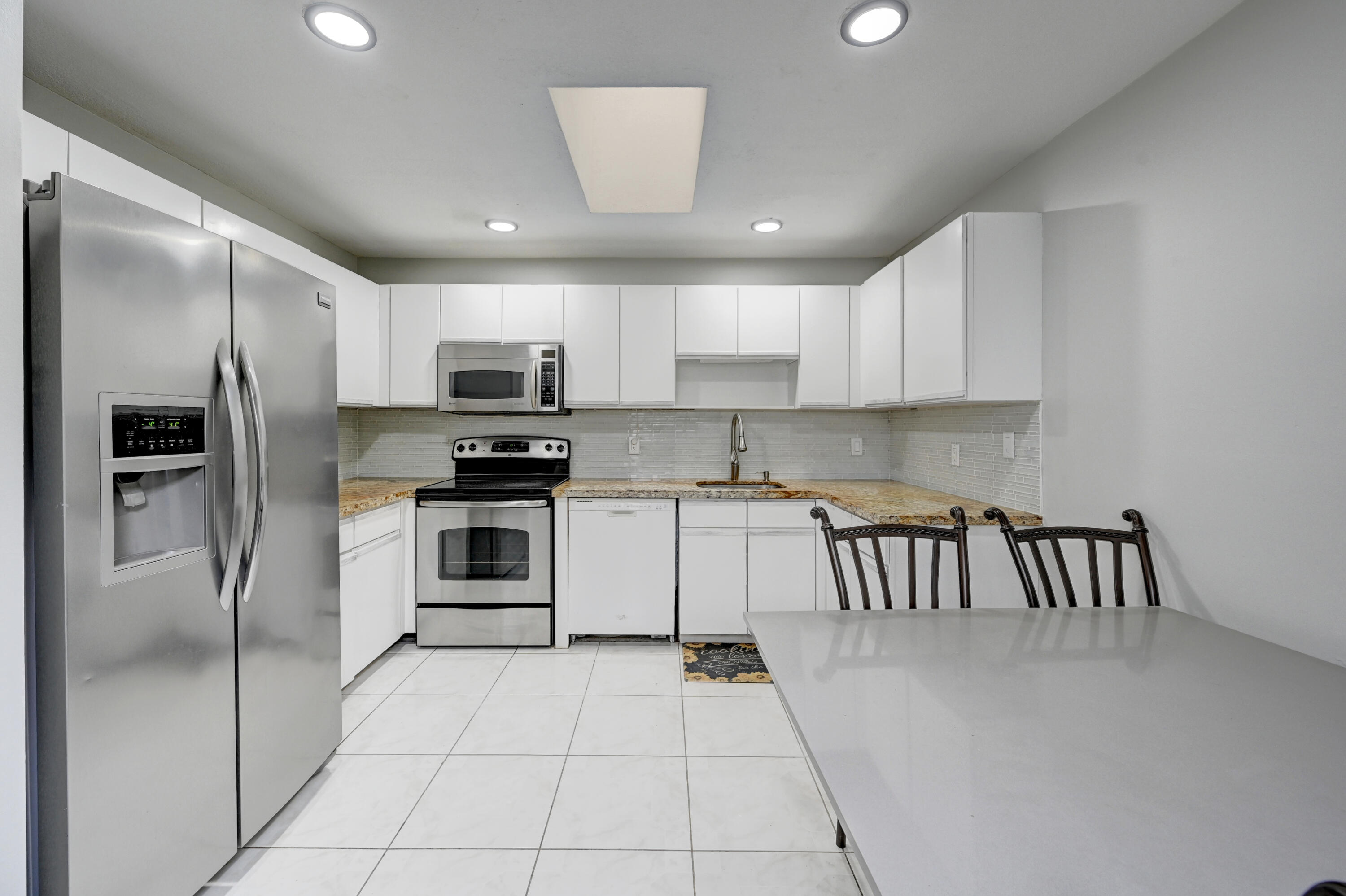 23328 Southwest 58th Avenue, Unit C Boca Raton, FL 33428 - Photo 10 of 35 a kitchen with granite countertop a refrigerator and a stove top oven