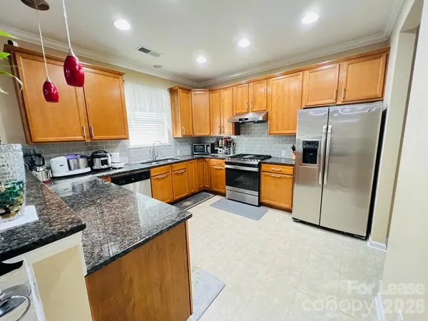 a kitchen with stainless steel appliances granite countertop a sink a stove and a refrigerator