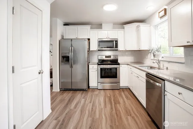 a kitchen with stainless steel appliances a refrigerator sink and wooden floor