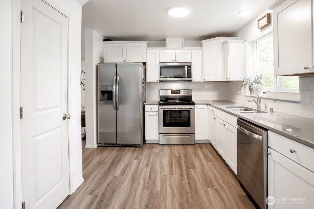 105 Johnson Road South Winlock, WA 98596 - Photo 9 of 32 a kitchen with stainless steel appliances a refrigerator sink and wooden floor