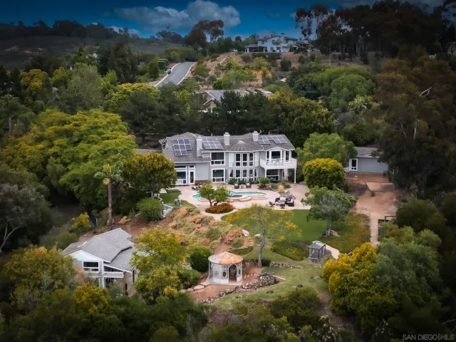 an aerial view of residential houses with outdoor space and trees