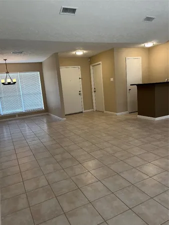 an empty room with kitchen view and windows