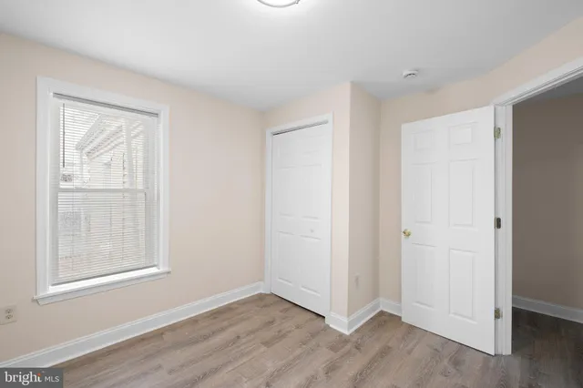 an empty room with wooden floor closet and windows