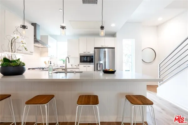 a kitchen with stainless steel appliances kitchen island granite countertop a sink a refrigerator and chairs