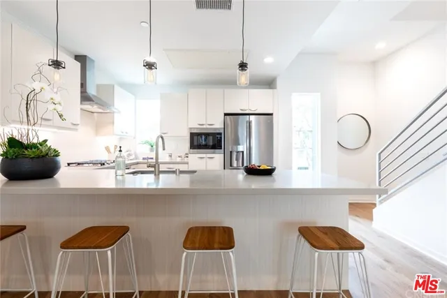 a kitchen with stainless steel appliances kitchen island granite countertop a sink a refrigerator and chairs